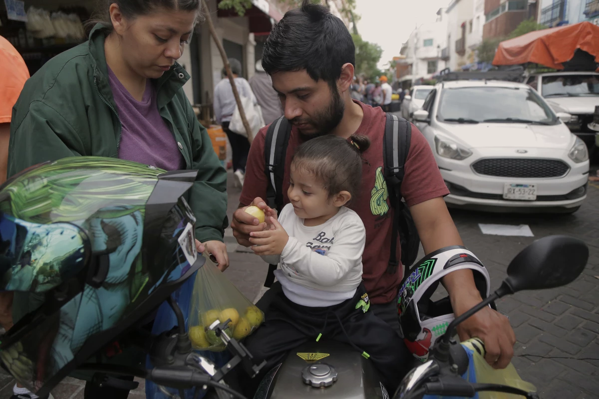 Son Tomás shares fruit that mom and dad purchased at the stalls on Zaragoza Street in the central area of Guadalajara. On their shopping excursion, they also bought enough meat to last for four days. They spent $27.