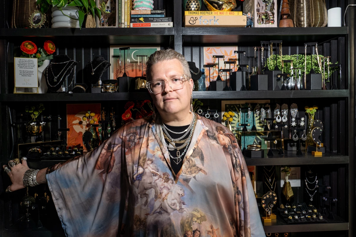 Jeffrey Burroughs stands in front of shelves of jewelry at their storefront in the River Arts District of Asheville, N.C.