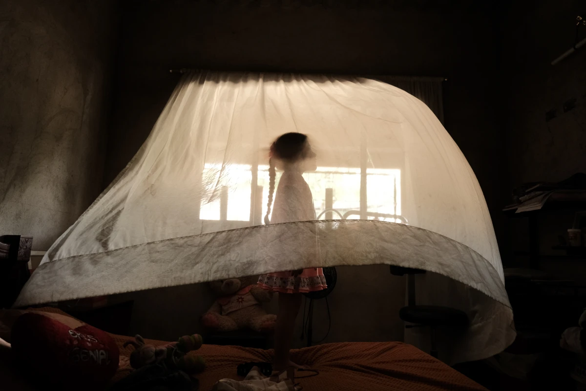 Valeria, age 5, plays behind a curtain at her aunt's house. She is raised solely by her mother. In her region, nearly a third of households are headed exclusively by women. Los Patios, Norte de Santander, Colombia. September 10, 2025.