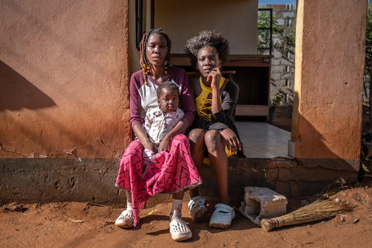 Janet Sikabonga, 36, and her daughter, Hilda Masombo, 17, of Livingstone, Zambia, sit on their front porch the morning after elephants raided their yard, destroying their water tap and laundry line. They say that elephants had previously destroyed their vegetable patch and fruit trees.