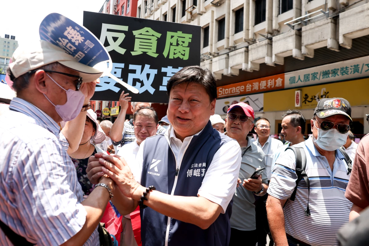 Fu Kun-chi (center), the leader of the Kuomintang (KMT) party caucus in Taiwan's legislature, shakes hands with supporters outside of the Legislative Yuan after voting for reconsidering bills at Parliament in Taipei on June 21, 2024.