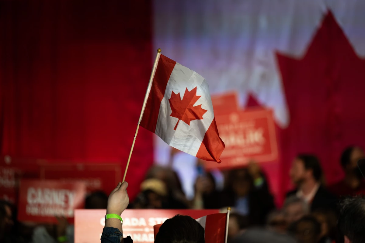 A supporter waves a Canadian flag during a campaign rally for Mark Carney, Canada's prime minister, in Calgary, Alberta, Canada, on Tuesday, April 8, 2025. Carney said Donald Trump's tariff policy is an act of economic self-sabotage that's pushing the US into a downturn. Photographer: Gavin John/Bloomberg via Getty Images