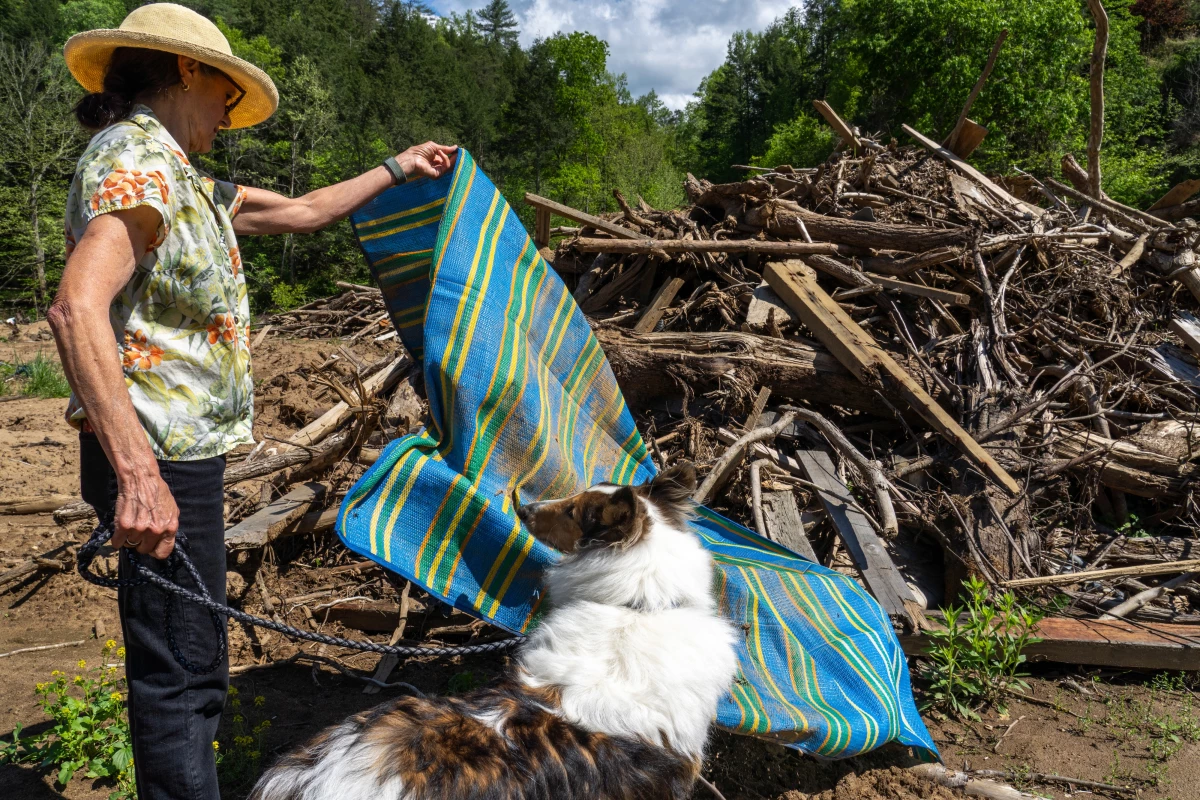 Sarah Bivins lifts a plastic woven mat from a pile of downed trees and debris that washed onto her farm property during the flooding from Hurricane Helene. 'It's still perfectly good. Just a few holes in it.'