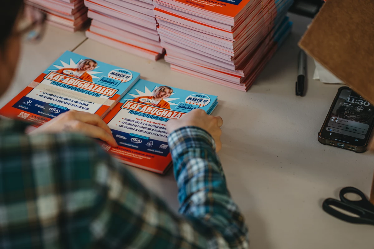 A campaign worker assembles mailers and informational materials for volunteers to distribute inside the Abughazaleh campaign office.