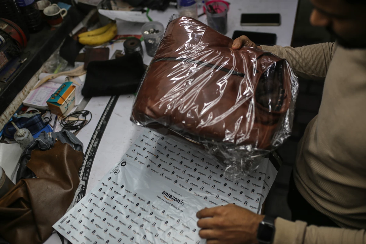 A worker packs a leather jacket in an Amazon India shipping bag at a workshop in the Dharavi area of Mumbai, India, on Jan. 5, 2022.