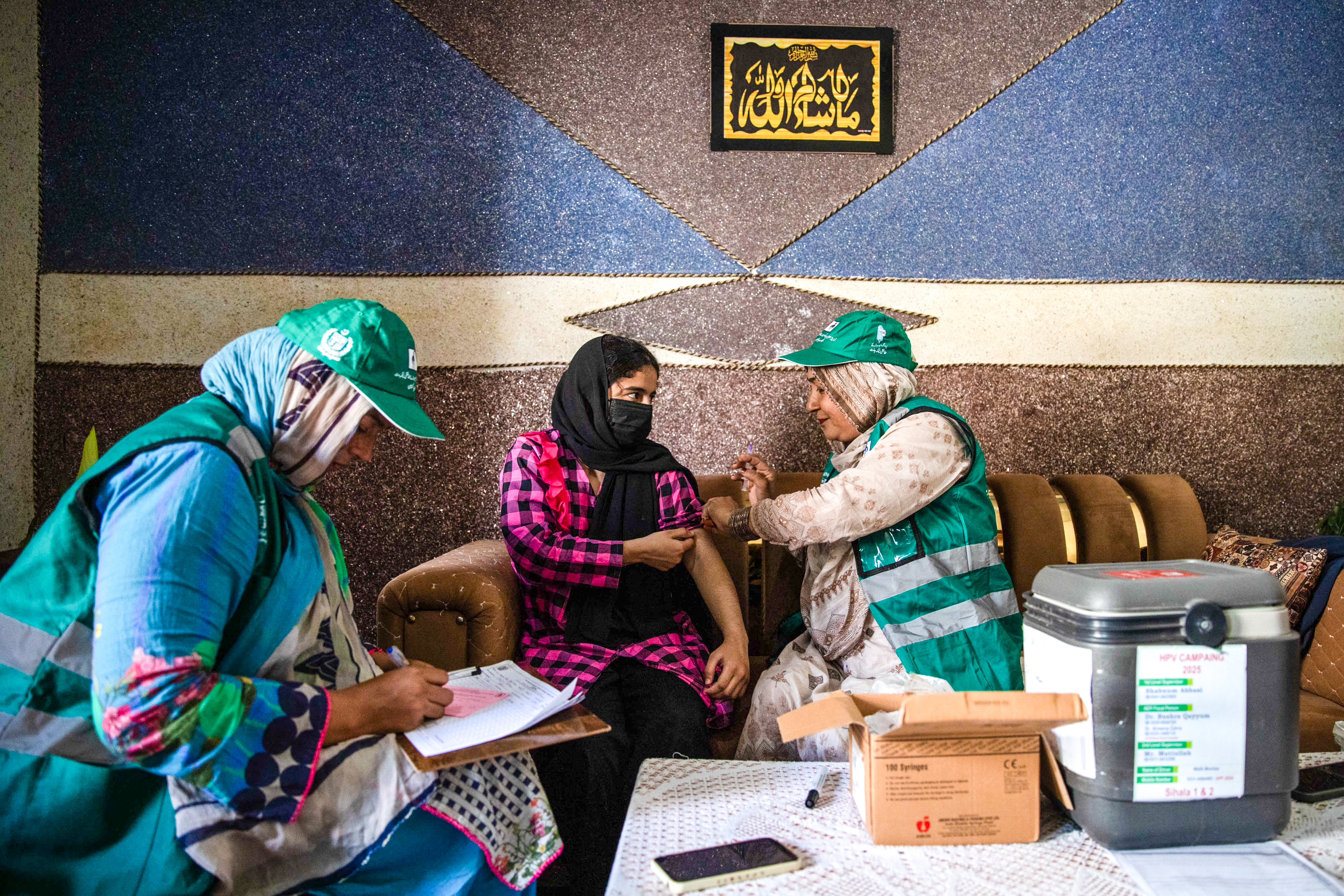 Vaccinators administer the HPV vaccine inside a home in Sihala in Islamabad, Pakistan.