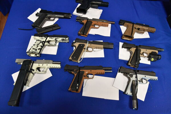Ten guns are displayed on top of a blue tablecloth.