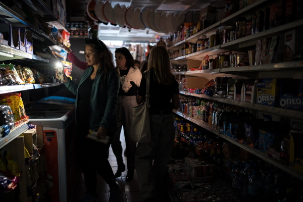 People shop for groceries using their phone as flashlight in Madrid, Spain on April 28.