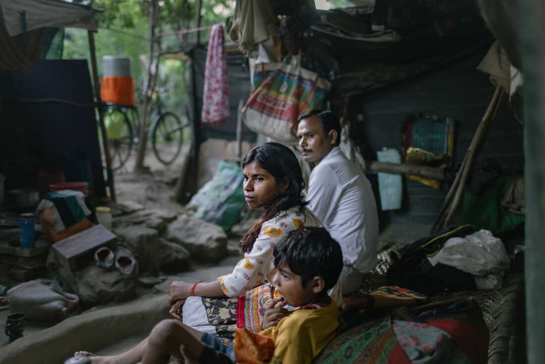 Kanchan and her son sit on his bed, next to Kamal, a relative, in the Muslim-majority neighborhood Bela Slum in New Delhi, India, October 13, 2026.