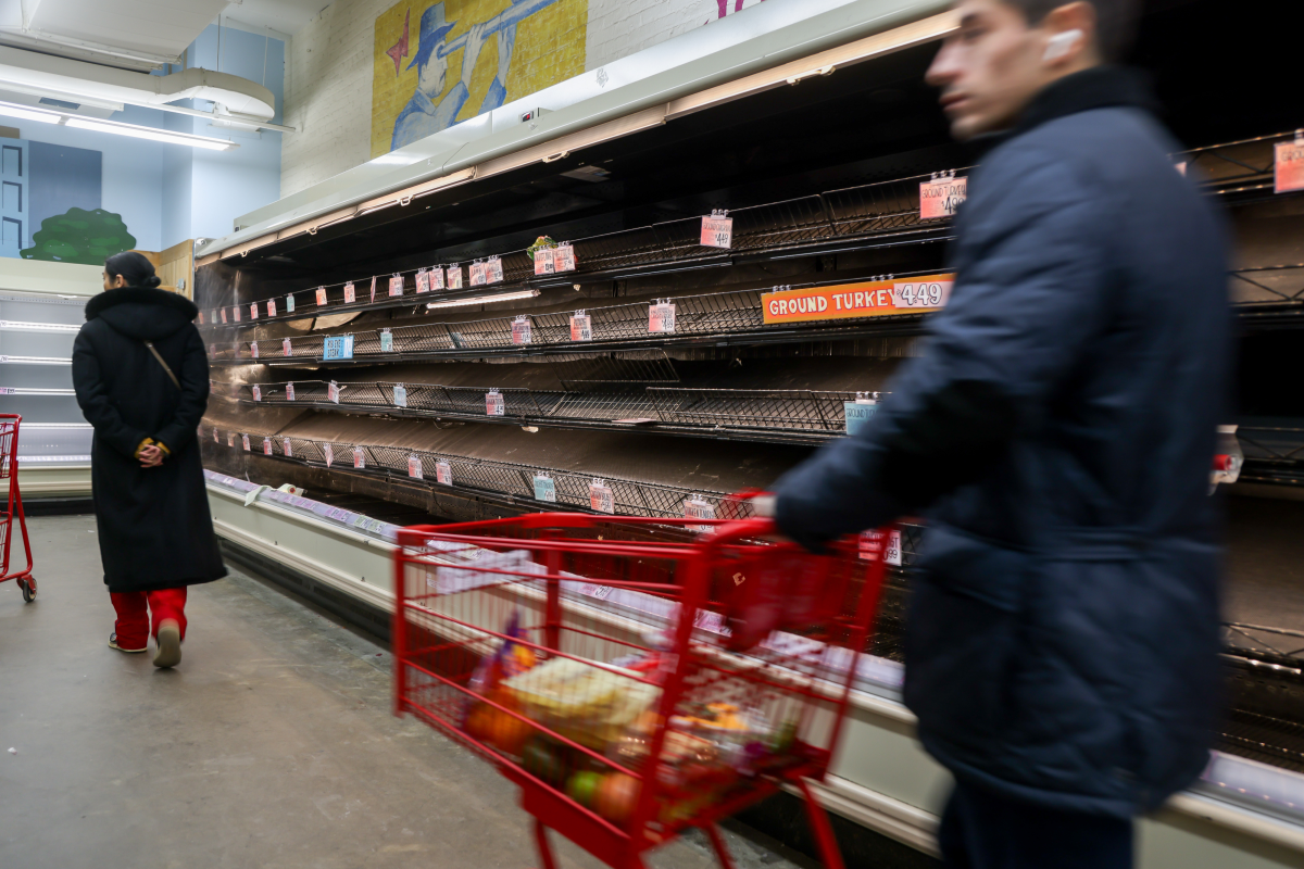 Shoppers walk past nearly empty shelves at a store ahead of an anticipated winter storm in New York.
