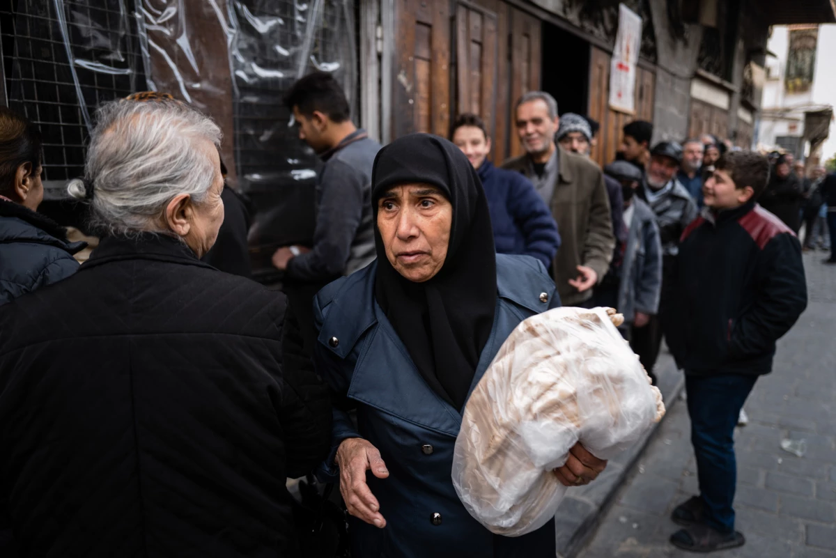 A woman collects her bread at a bakery in the Syrian capital Damascus. Bread costs up to ten times more than it did just weeks ago — from 400 Syrian lira to 4,000 Syrian lira for a dozen pieces of dinner-plate-size flat bread. That new price is the equivalent of 31 cents.