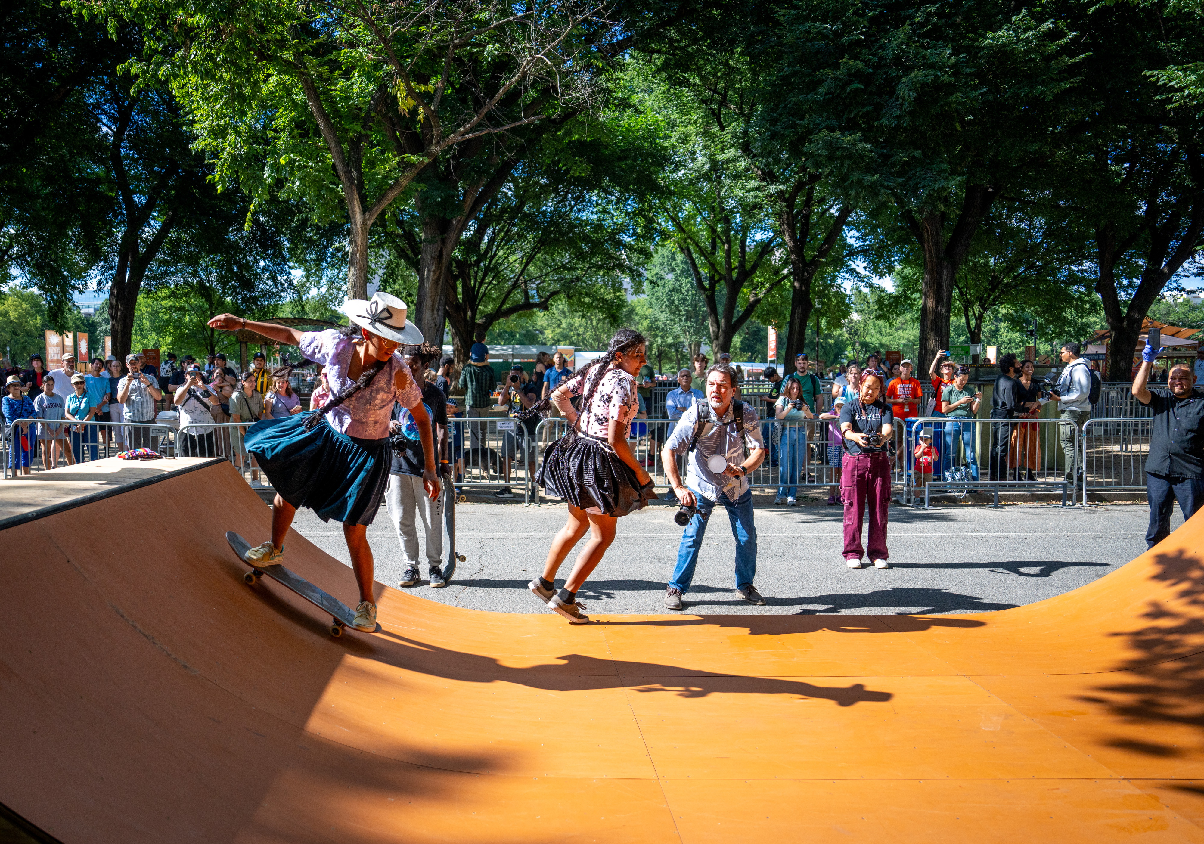 Bolivian women skateboarders — wearing traditional garb — demonstrate their skills on the half pipe.