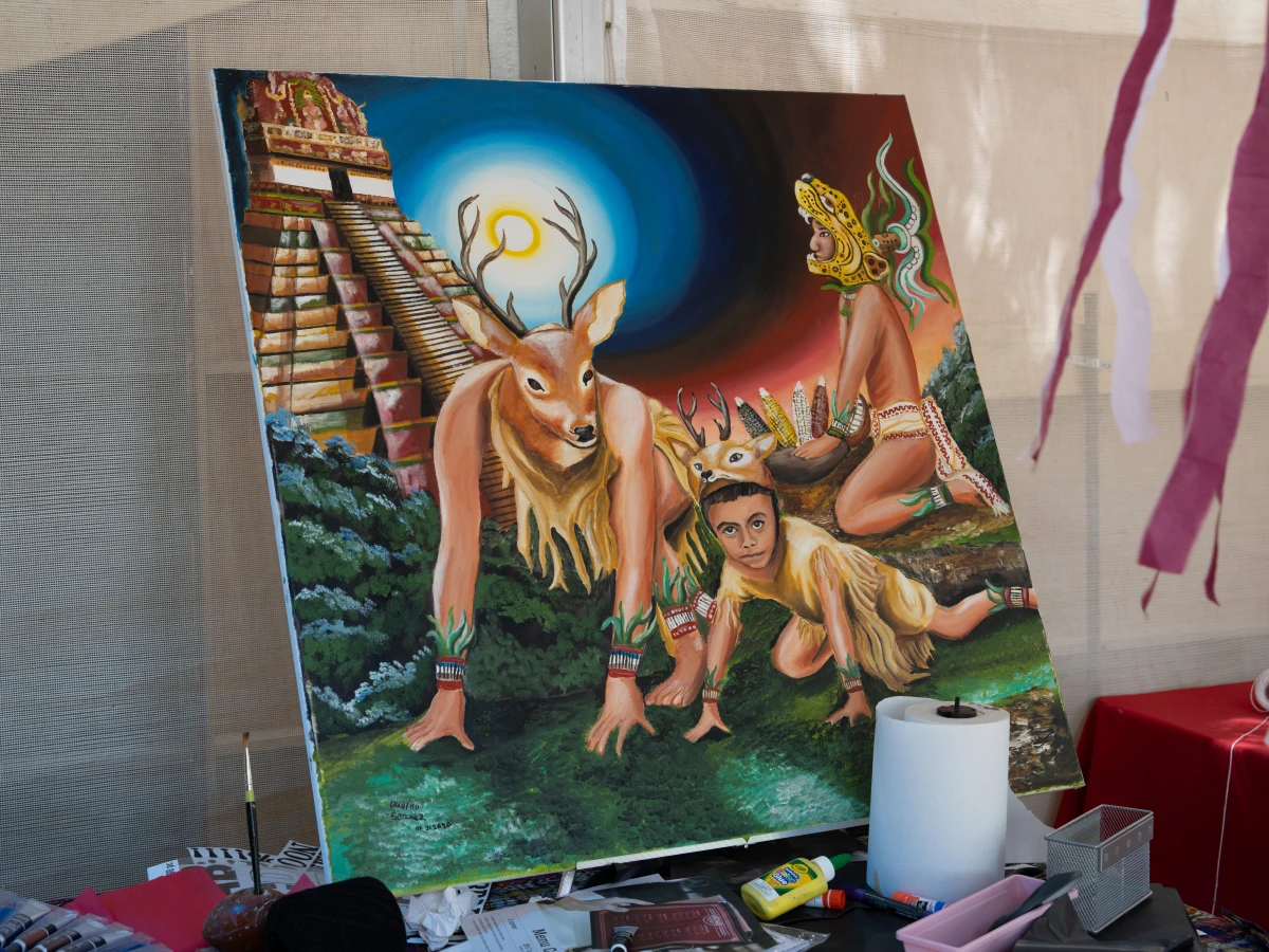 This painting, 'Dance of the Deer' by Ubaldo Sanchez, depicts a traditional Maya ceremony held before hunting deer. The characters in the painting are Sanchez's grandfather (at left wearing the deer head); his young nephew Kevin Cabrera Sanchez (also in a deer costume) and Sanchez himself dressed as a jaguar.