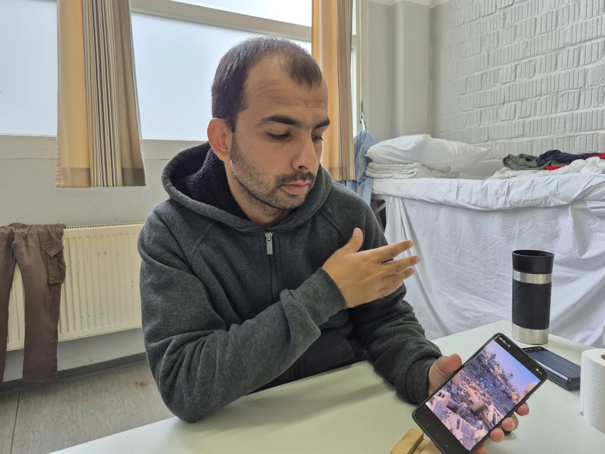 Mohammed Abu Daqqa, a 31-year-old Palestinian who left Gaza, scrolls through images on his phone at a refugee welcome center in Germany. He describes how he rode a jet ski across the Mediterranean to take refuge in Europe, and is determined to get his family out of Gaza.