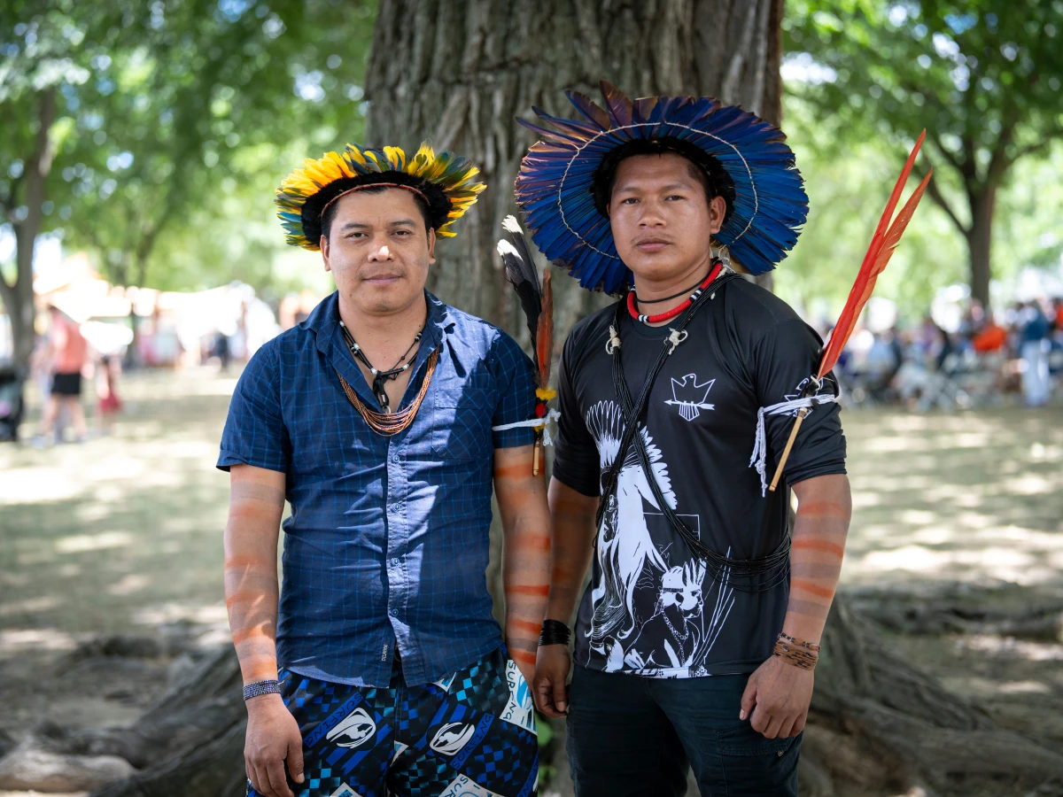 Tambura Amondawa (left) sports the bright yellow-orange feathers of the macaw that is their symbol of his clan. At right is Tupi Kawahin, who wears the deep blue feathers of his clan's mutuanaguera bird symbol. Together they sang a song, composed by Tambura's grandfather, celebrating the survival of their Indigenous community.