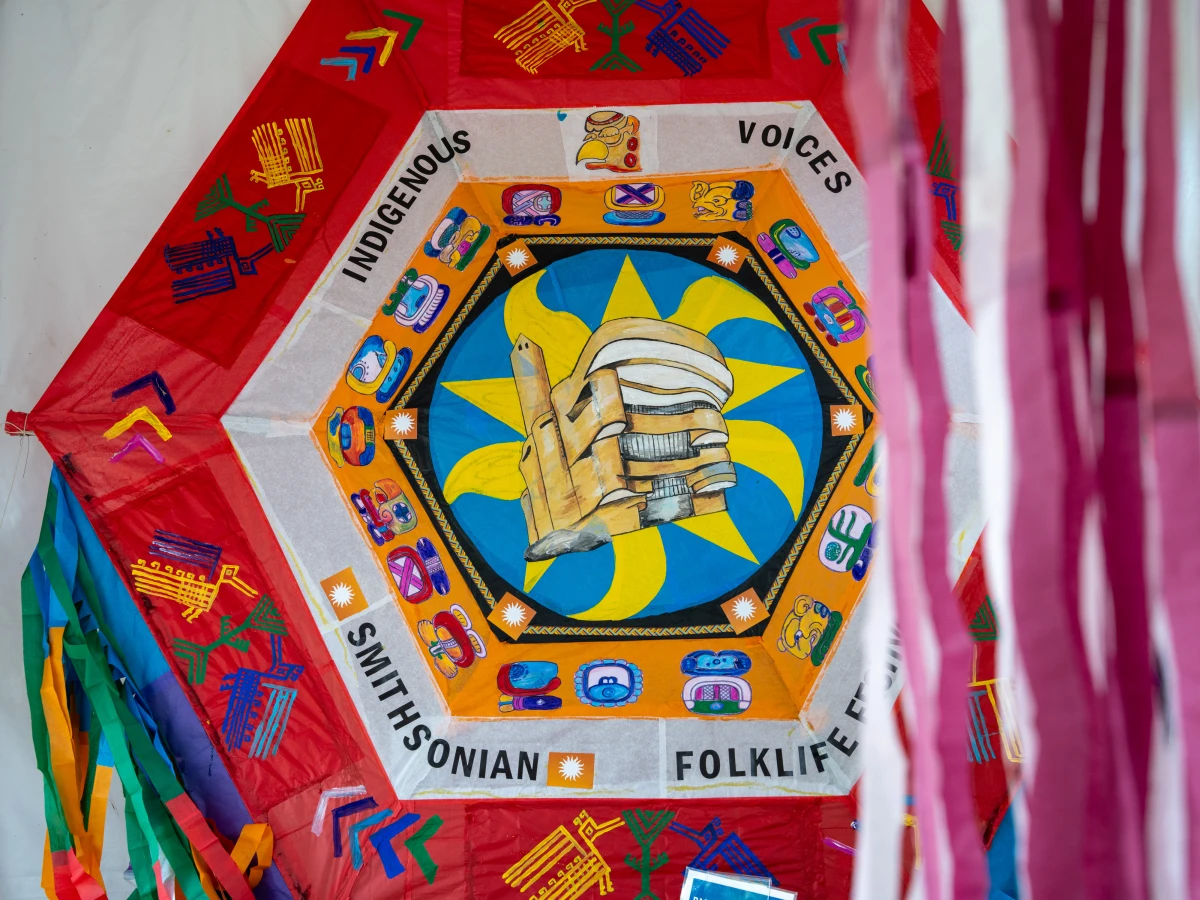 At the Folklife Festival, Ubaldo Sanchez painted Maya symbols on a giant kite honoring the 20th anniversary of the National Museum of the American Indian. Its building is depicted in the center of the kite, which is being donated to its collection.