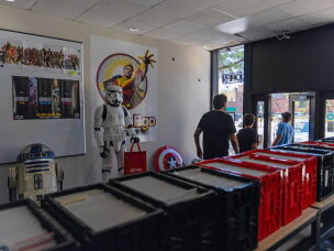 Customers walk by lifesize models of R2-D2 and a Stormtrooper from <em>Star Wars</em> as they exit the store.