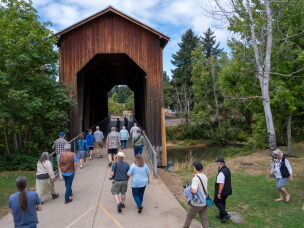 Conference attendees cross the Chambers Covered Railroad Bridge during a tour in Cottage Grove, Ore.