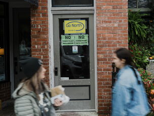 Pedestrians walk past data center protest signs on Front Street in Thomas, W.Va.