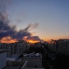 A person standing on the roof of a building looks at a plume of smoke rising after a strike on the Iranian capital, Tehran, on Tuesday.