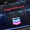 The logos for ExxonMobil and Chevron appear on display screens on the floor of the New York Stock Exchange during morning trading on July 24.