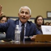 Dr. Anthony Fauci is seated at a table with a microphone and a water bottle in front of him.