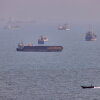 A small boat sails past cargo ships and other commercial vessels anchored in the Strait of Hormuz off Bandar Abbas, Iran, on Aug. 5.
