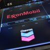 The logos for ExxonMobil and Chevron appear on display screens on the floor of the New York Stock Exchange during morning trading on July 24.
