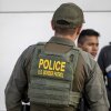 A U.S. Border Patrol agent watches as immigrants prepare to board a bus after crossing the U.S.-Mexico border.