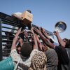 Sudanese families displaced from El-Fasher reach out as aid workers distribute food supplies at the newly established El-Afadh camp in Al Dabbah, in Sudan's Northern State, Sunday, Nov. 16, 2025.