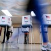 Voters cast their ballots in Oak Creek, Wis., in 2024. The voting booths have American flags printed on them and the word "Vote."