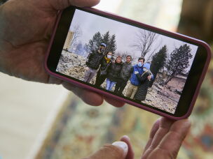 Louie Delaware holds his phone showing a photo of his family outside of their burned home after the Marshall Fire, which destroyed more than 1,100 homes in Louisville, Superior and unincorporated Boulder County.