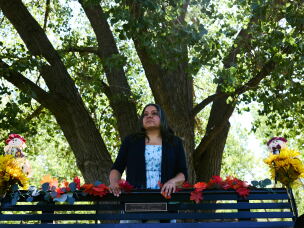 Montoya stands behind a bench, on a trail near her home, with a plaque in memory of Juliana.