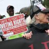 Demonstrators walk in Selma, Ala., in March with a sign saying “UNITE TO FIGHT FOR VOTING RIGHTS” to commemorate the 60th anniversary of the Bloody Sunday march that galvanized the passage of the Voting Rights Act of 1965.