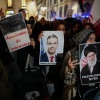 Demonstrators hold photographs of Spain's prime minister and the killed Iranian supreme leader.