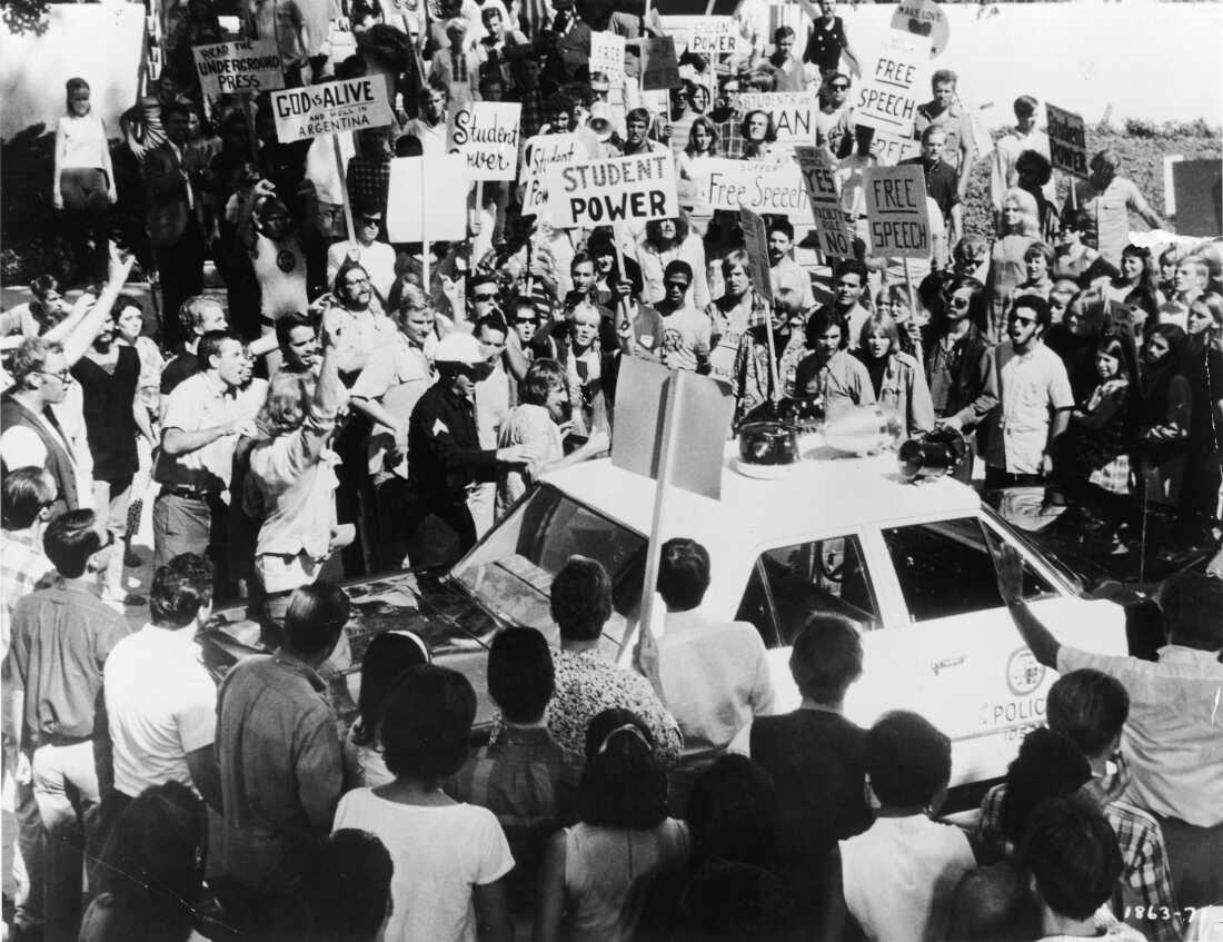 Un policier escorte un manifestant jusqu'à une voiture de police entourée de dizaines de manifestants anti-guerre du Vietnam à l'extérieur de la Convention nationale démocrate de 1968 à Chicago. (Photo de Hulton Archive/Getty Images)