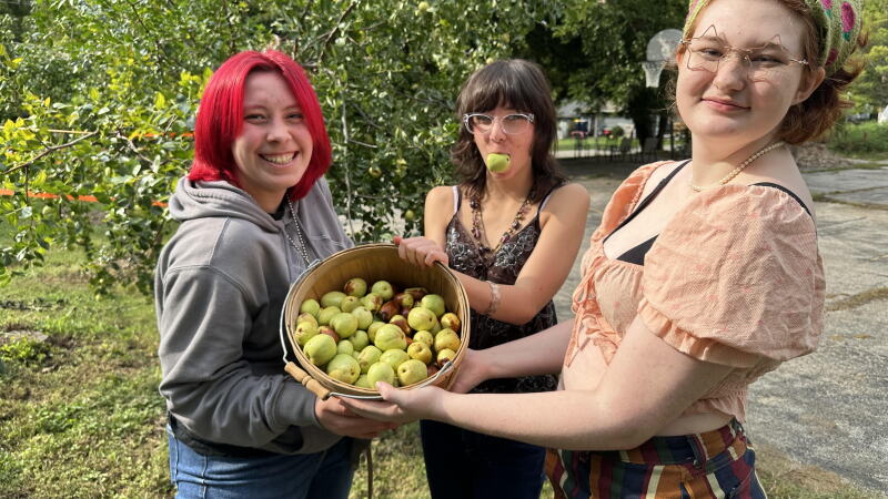 Kansas City Academy students Peper Wilson, Alex Ledford, and Nova Henry are showing off a basket of jujubes freshly picked from trees the Giving Grove helped the school plant and maintain.