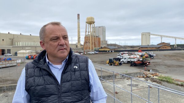 Chris Mikkelsen, a man in a button-down shirt and puffer vest, stands on the site of a planned marine terminal in Eureka, Calif. 