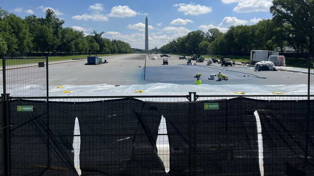 Workers paint a corner of the reflecting pool blue on Monday morning.