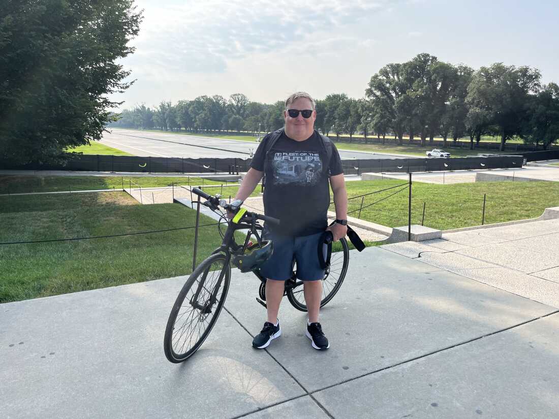 Joe Flood poses with his camera and bike near the reflecting pool on Monday. 