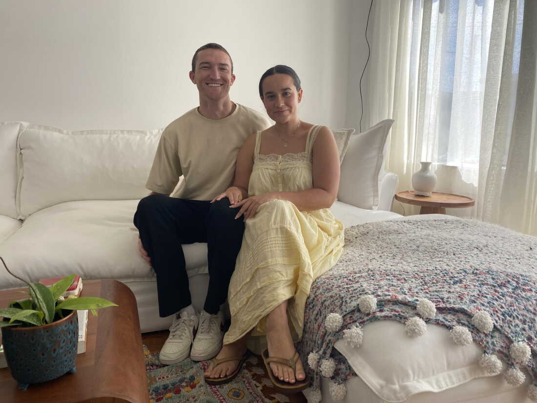 Aidan Cahill and Ally Alessio sit on a white sofa in the apartment they moved into in August.