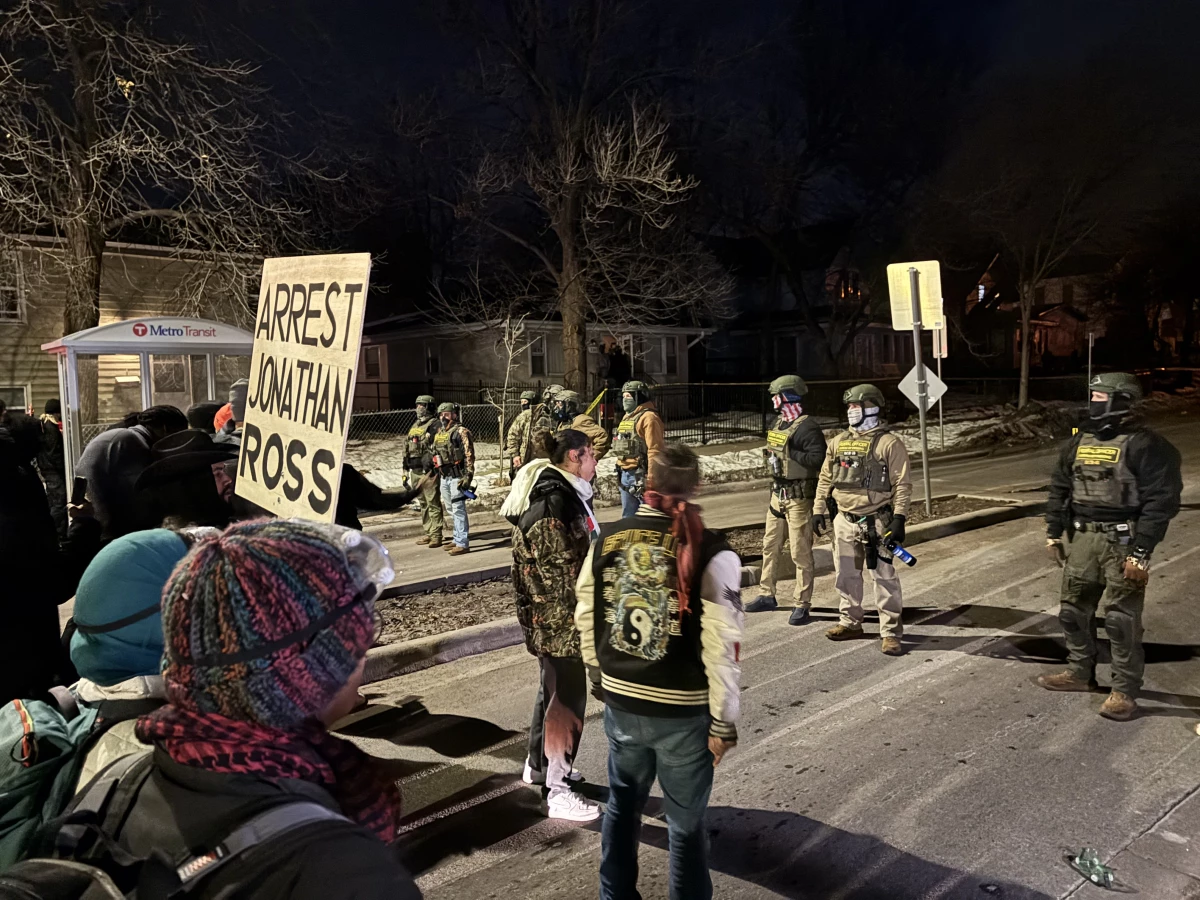Demonstrators stand in front of federal immigration agents protecting the scene where an Immigration and Customs Enforcement agent shot a Venezuelan immigrant in the leg on January 15, 2026 in Minneapolis.