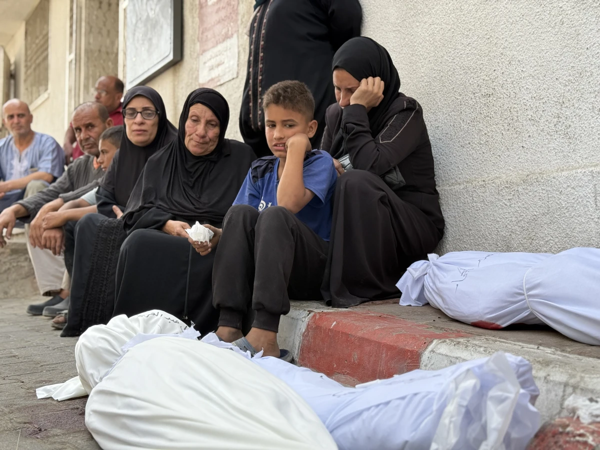 Members of the Nasser family sit with the bodies of their relatives at the morgue of Shifa hospital in Gaza City following an airstrike that killed 20 Palestinians according to Gaza health officials, on May 18, 2025.