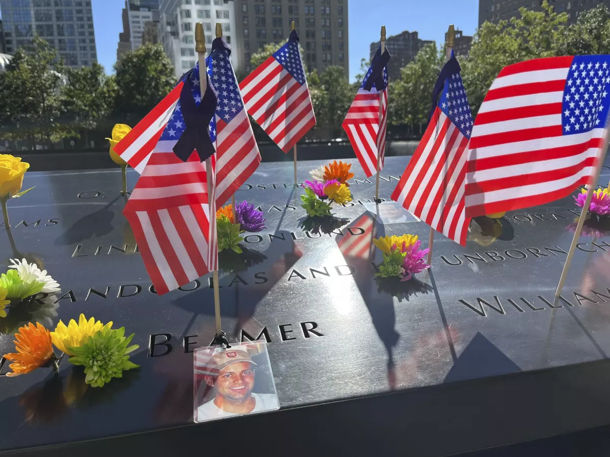 Flags and flowers are placed by the names of those killed during the Sept. 11, 2001, attacks at the reflecting pools at the National September 11 Memorial & Museum on Tuesday in New York.