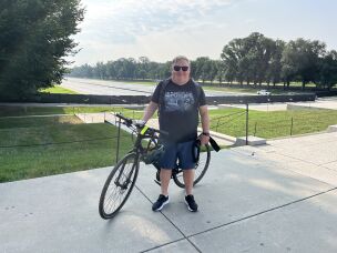 Joe Flood poses with his camera and bike near the reflecting pool on Monday. The D.C.-based photographer has been posting near-daily updates on social media since the renovations began.