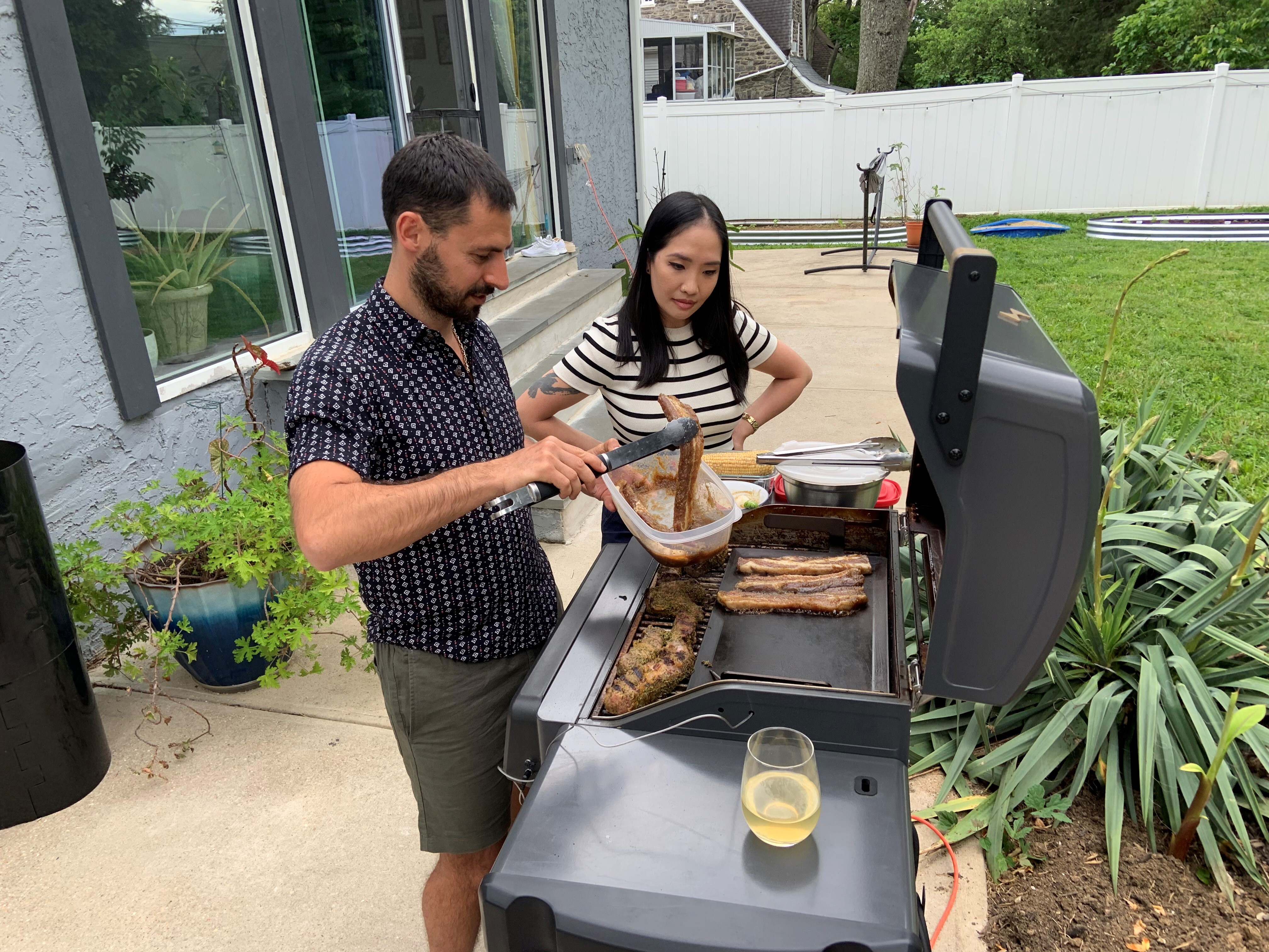 Stoio Kachev and Doanh Nghiem cook dinner on their electric grill. The couple says convenience is the main reason they switched from a propane grill — no need to refill tanks. Switching to electric also reduces their contribution to climate change. (NPR)