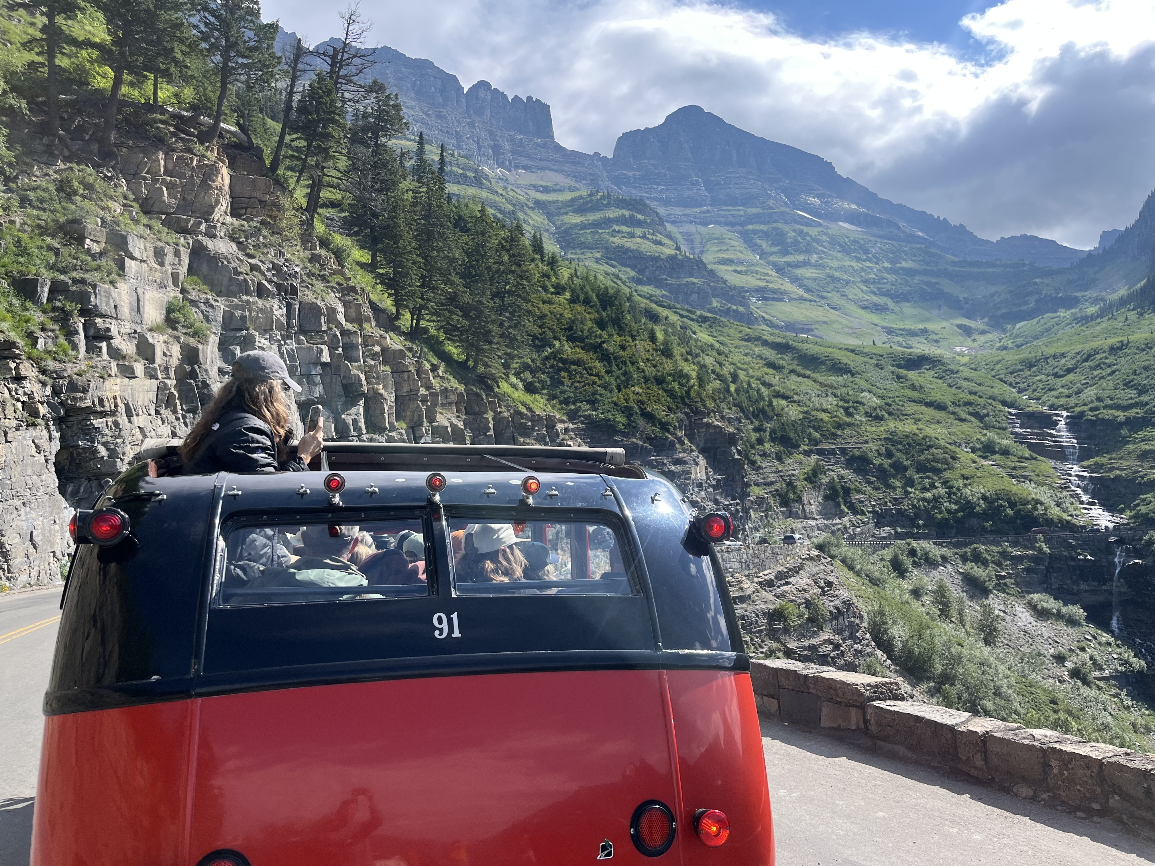 Along Glacier National Park's Going to the Sun Road, tourists admire the view from one of the park's vintage red buses (NPR)