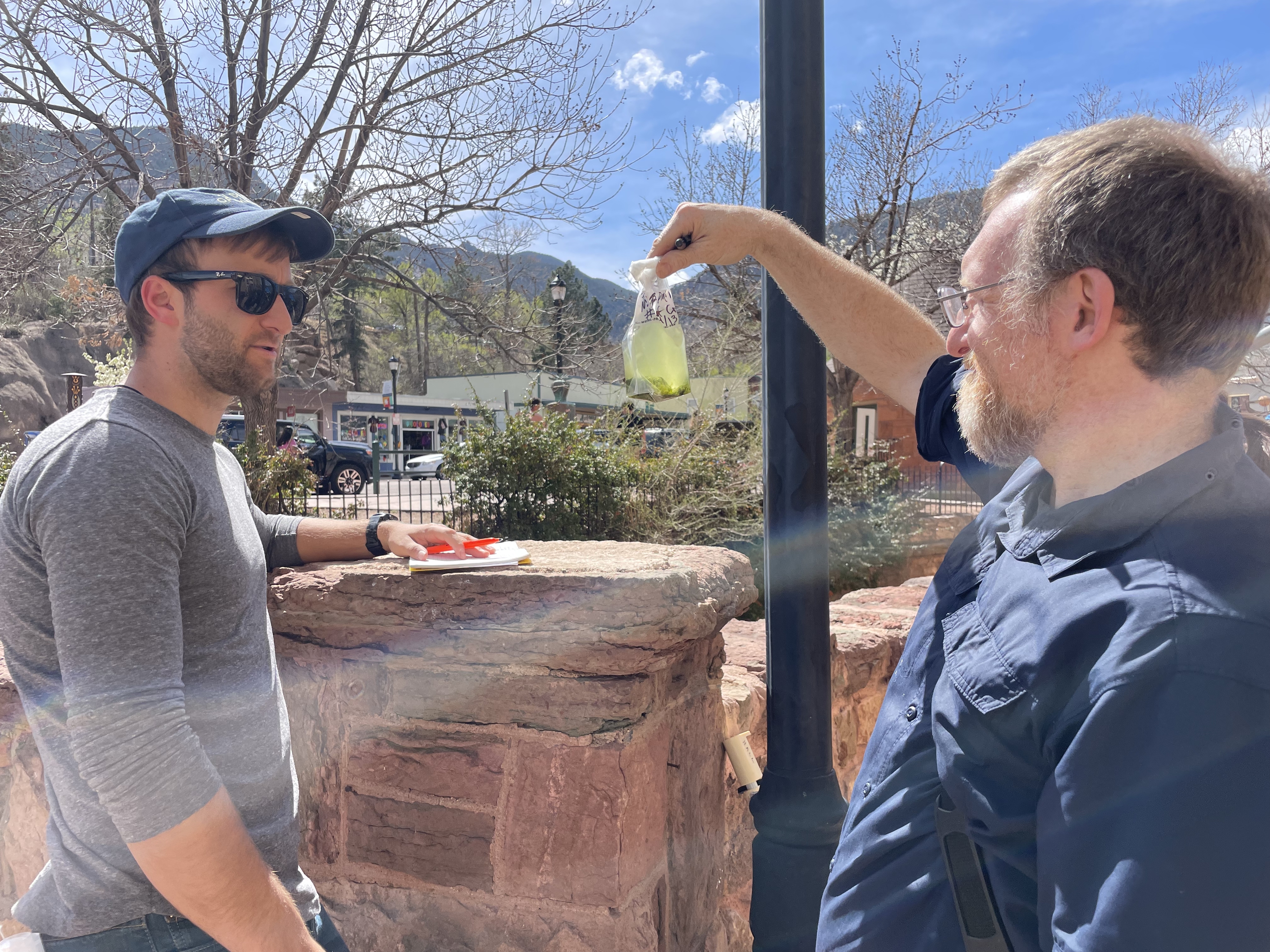 James Henriksen with Colorado State University, holds up a water sample for Harvard colleague Braden Tierney. The bag is teeming with microbes that they hope may help solve some of humanity