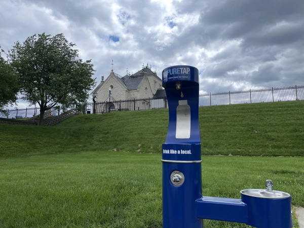 A Louisville Water Co. drinking fountain, with a pump house in the distance.
