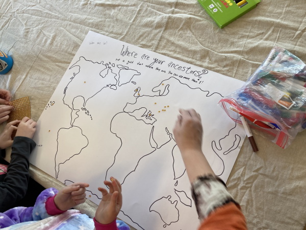 Children place gold stickers on a hand drawn map on a posterboard.